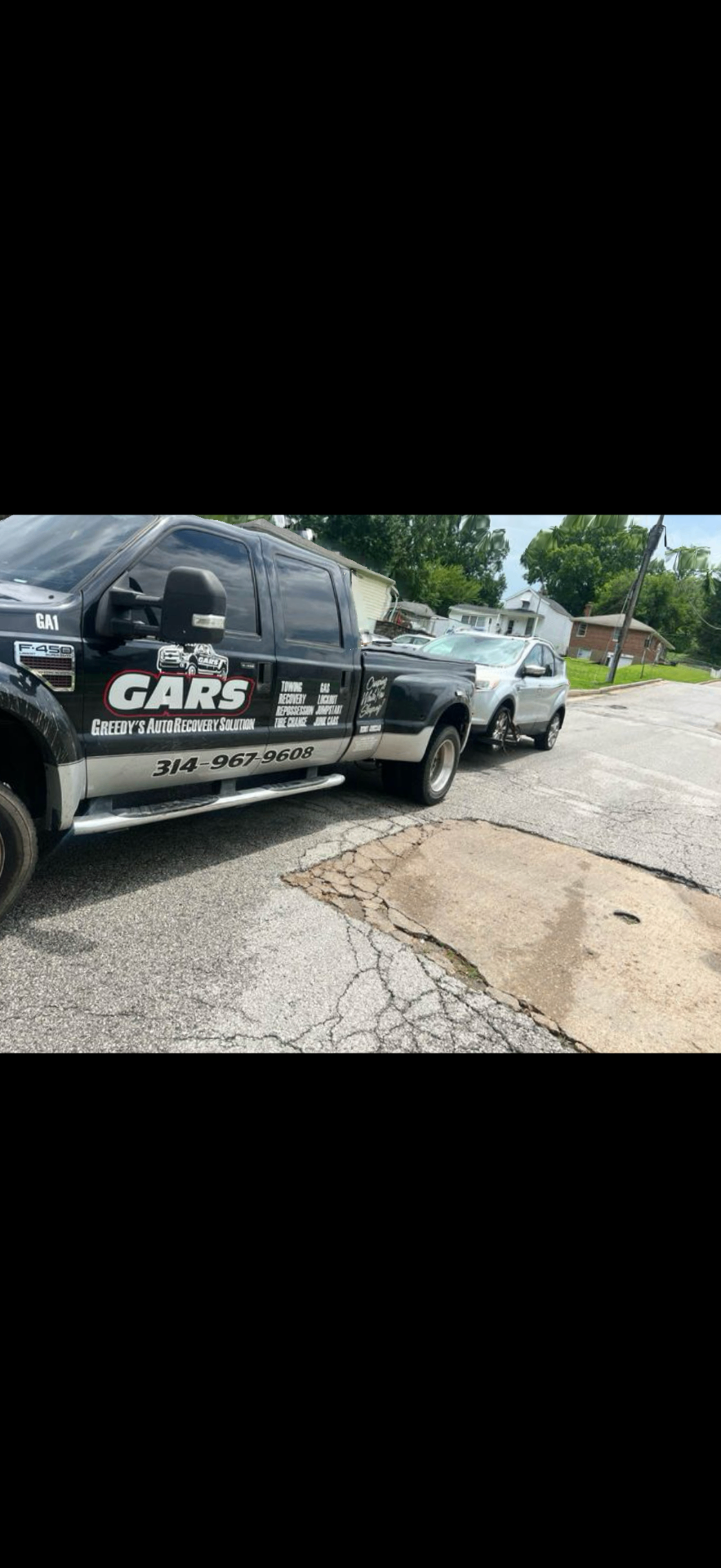 GARS flatbed tow truck loading a luxury vehicle at night